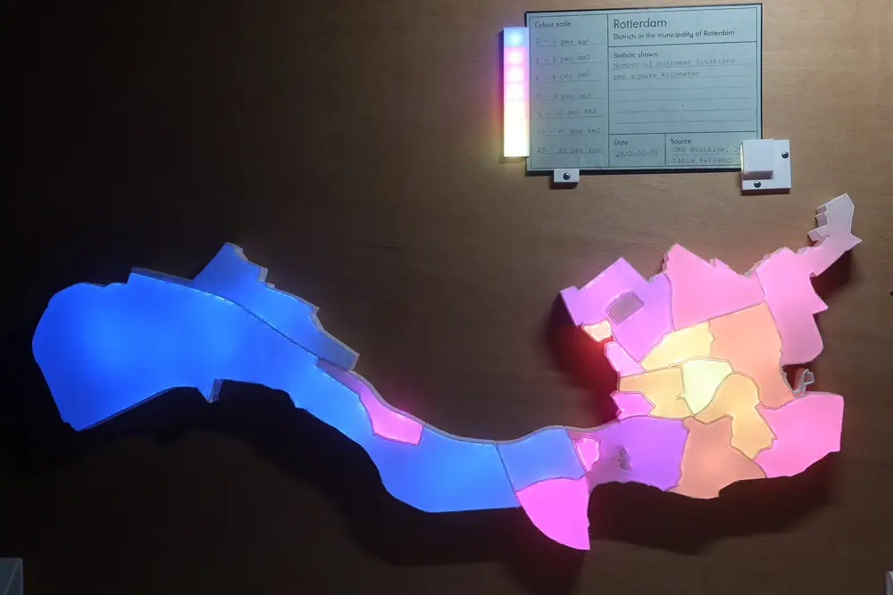 Picture of the visualisation with a card inserted. All neighbourhoods are lighted up with different colours ranging from purple to light yellow. At the top the green card showing the description of the data and a legend going from 0 to 25 per square km.