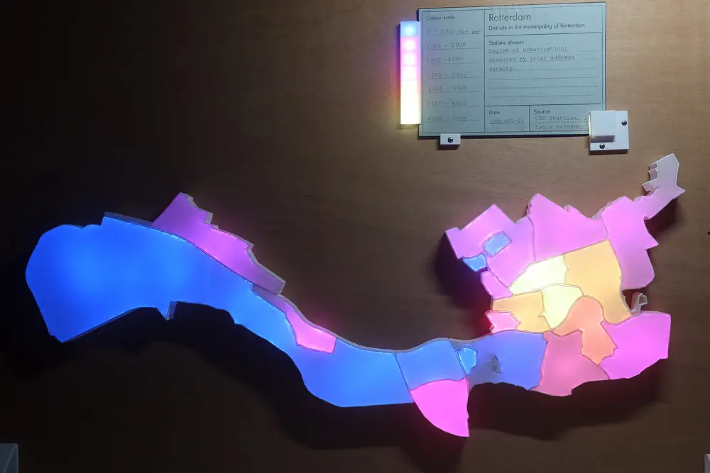 Picture of the visualisation with a card inserted. All neighbourhoods are lighted up with different colours ranging from purple to light yellow. At the top the green card showing the description of the data and a legend going from 0 to 7 000 per square km.