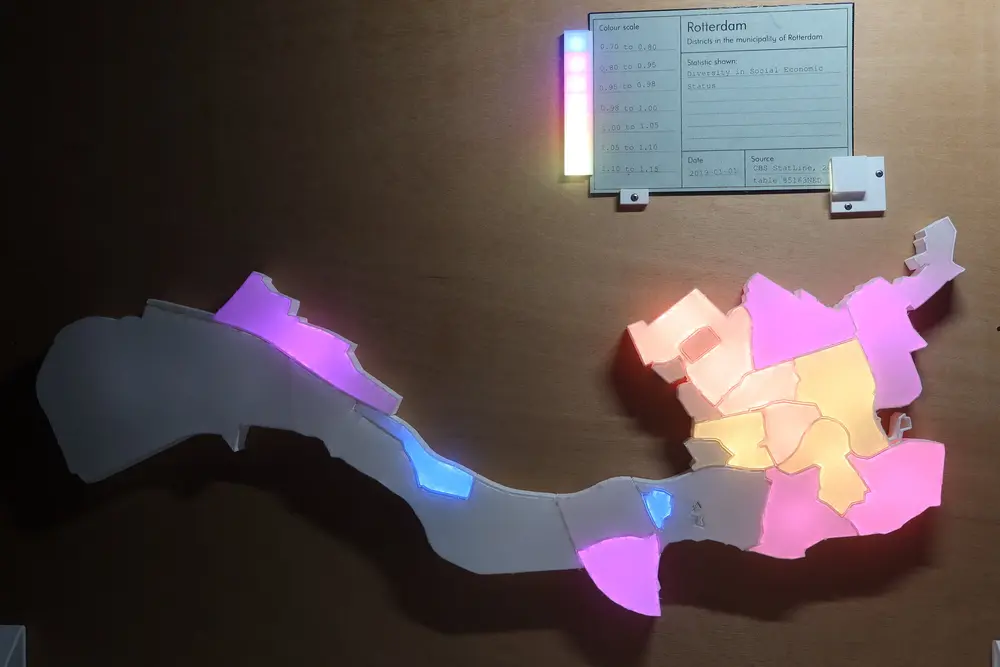 Picture of the visualisation with a card inserted. Some of the neighbourhoods are lighted up with different colours ranging from purple to light yellow. At the top the green card showing the description of the data and a legend going from 0.70 to 1.15.