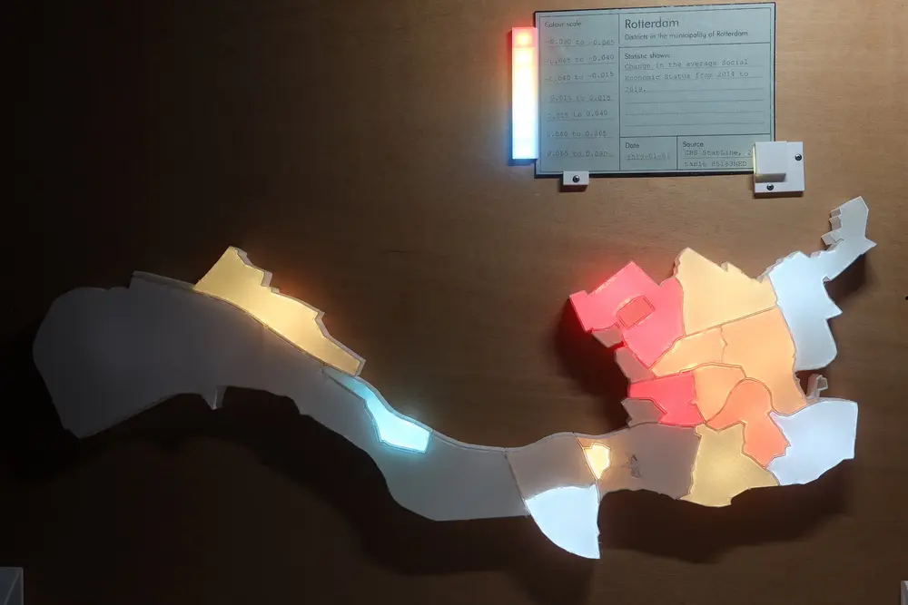 Picture of the visualisation with a card inserted. Some of the neighbourhoods are lighted up with different colours ranging from red to yellow to light blue. At the top the green card showing the description of the data and a legend going from -0.09 to 0.09.